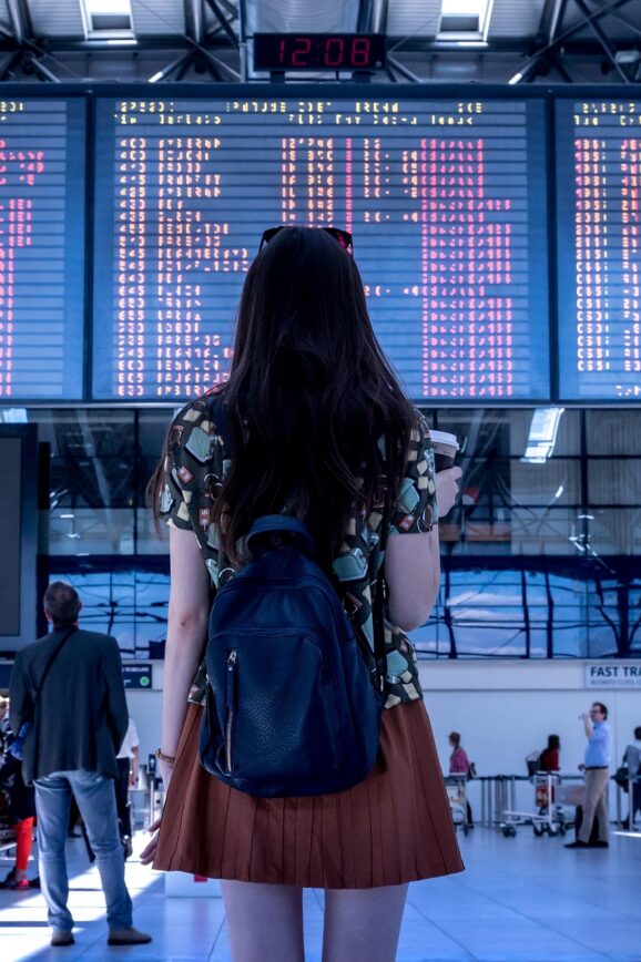 Traveler with a backpack checking the departure board at an airport terminal