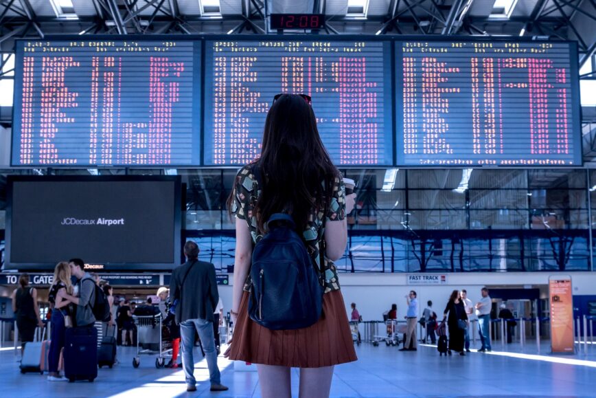 Traveler with a backpack checking the departure board at an airport terminal