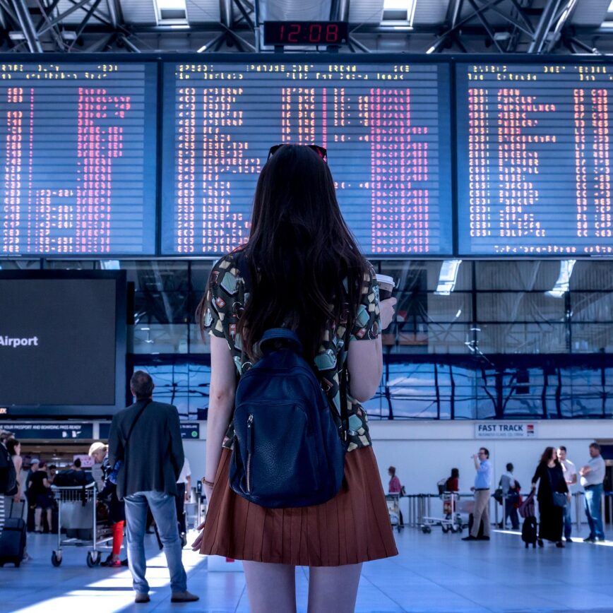 Traveler with a backpack checking the departure board at an airport terminal