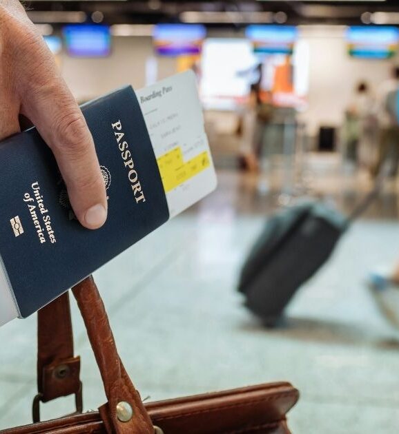 Traveler holding a passport and suitcase at an airport