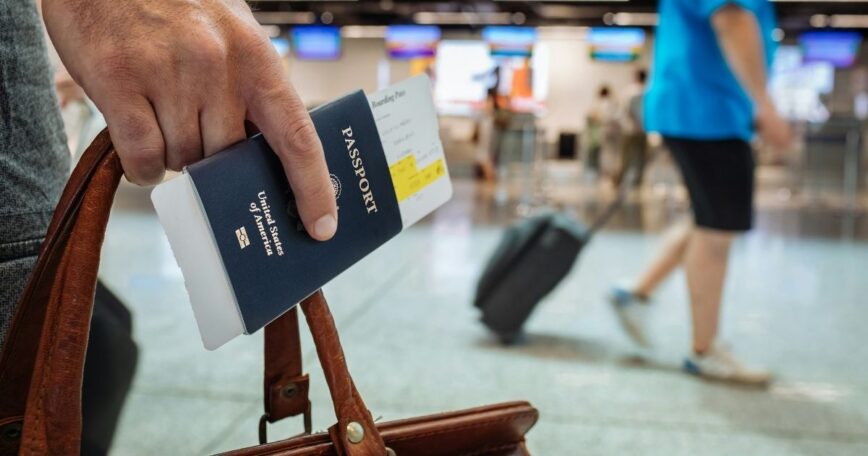 Traveler holding a passport and suitcase at an airport