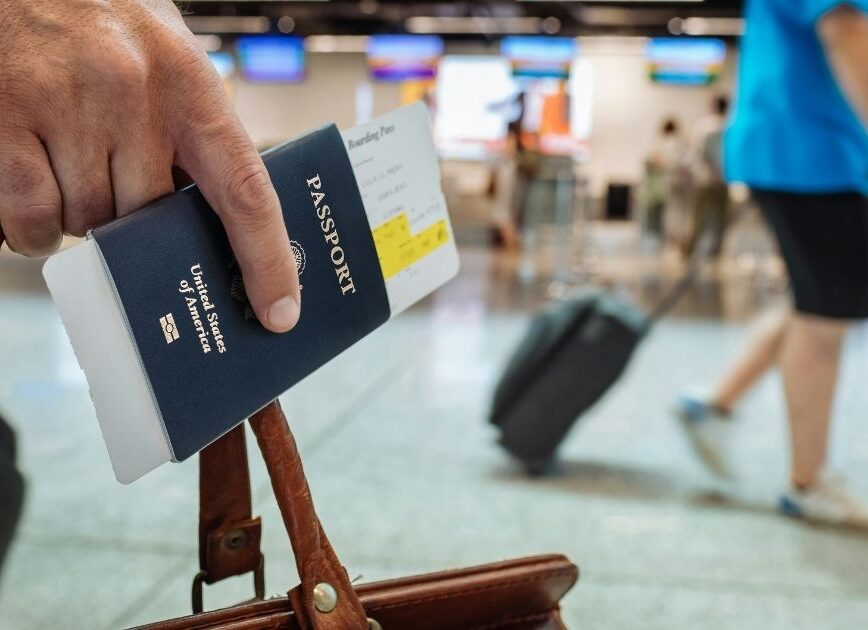 Traveler holding a passport and suitcase at an airport